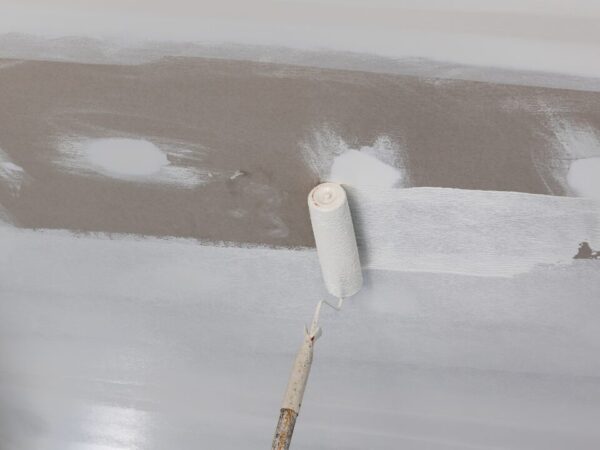 Worker painting a gypsum ceiling panel